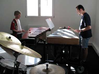 Das Bild zeigt links einen Jungen und rechts einen Mann an den neuen Instrumenten der Musikschule.