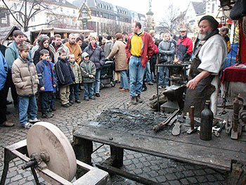 Das Foto zeigt den Schmied vom Mittelalterlichen Markt  und viele Kinder, die zuschauen