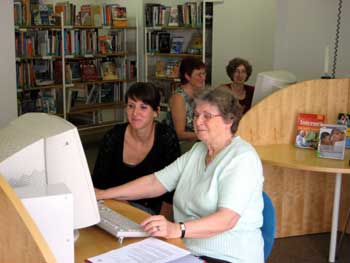 Das Bild zeigt eine junge Frau, die neben einer Seniorin am Computer sitzt und ihr das Internet zeigt. 