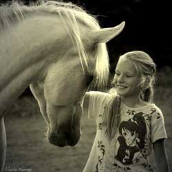 Das Bild zeigt ein Mädchen, dass ein Pferd streichelt.