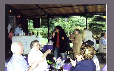 Das Foto zeigt einige Gäste beim Sommerfest in die Hände klaschend an Tischen sitzend