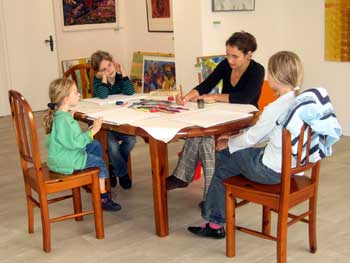 Drei Mädchen und ihre Lehrerin beim Malen