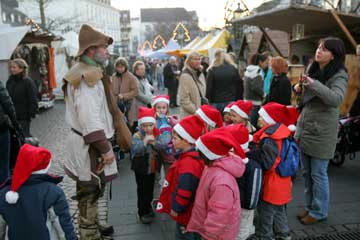 Kinder mit roten Weihnachtsmützen bei der Stadtführung auf dem mittelalterlichen Weihnachtsmarkt