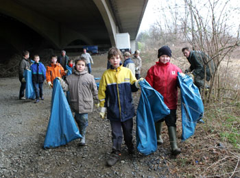 Viele Kinder sammeln gemeinsam mit ihren Eltern Unrat unter einer Brücke