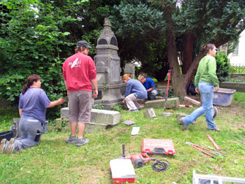 Das Bild zeigt die Steinmetzschüler beim Restaurieren der Grabsteine