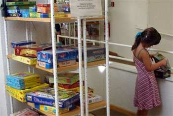 Das Bild zeigt ein Mädchen neben dem Spieleregal in der Stadtbibliothek