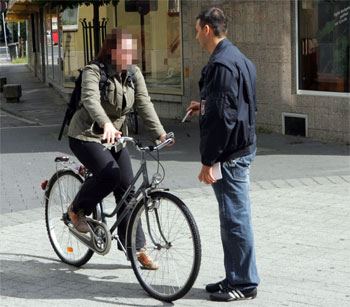 Ein Mitarbeiter des Ordnungsamtes hält eine Radfahrerin an