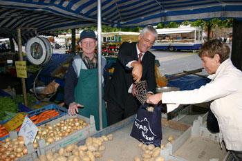 Bürgermeister Franz Huhn füllt auf dem Markt Kartoffeln in das Stadtsäckel