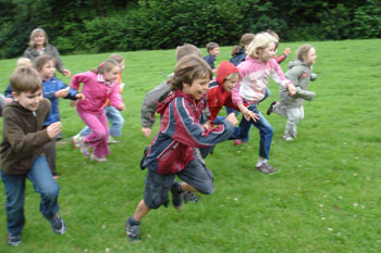 Kinder laufen fröhlich auf einer Wiese 