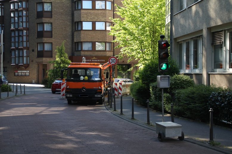 2020-05-06_Mühlenstraße Baustellenfahrzeug in einer Kurve, der Verkehr wird durch eine grün zeigende Ampel geregelt