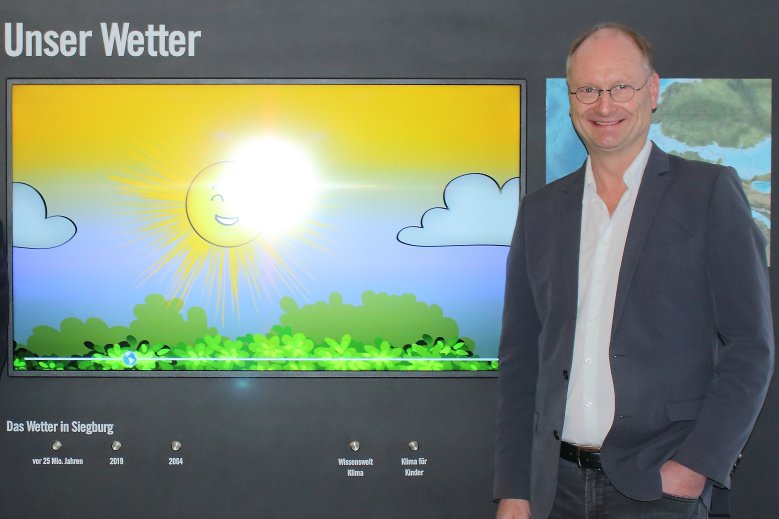 2020-05-15_Ploeger Ein Mann, Sven Plöger, steht neben einem Bild mit einer animierten Sonne