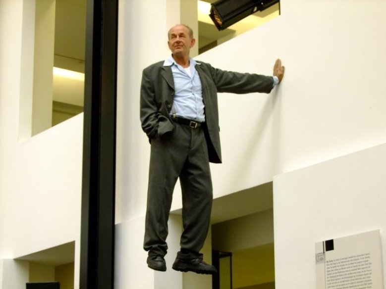 2020-05-17_museum Scheinbar in der Luft schwebender Mann stützt sich an einer Wand ab
