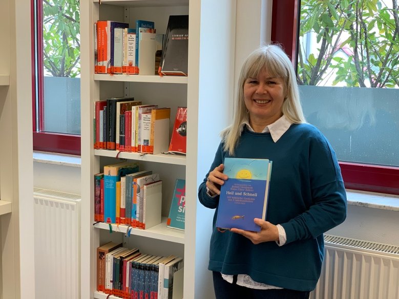 Jolanta Magg Jolanta Magg vor einem Bücherregal, in der Hand hält sie ein Buch