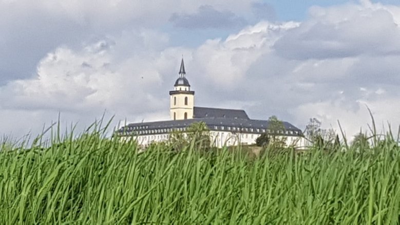 St. Michael und KSI-Gebäude zwischen grünem Gras und bewölktem Himmel