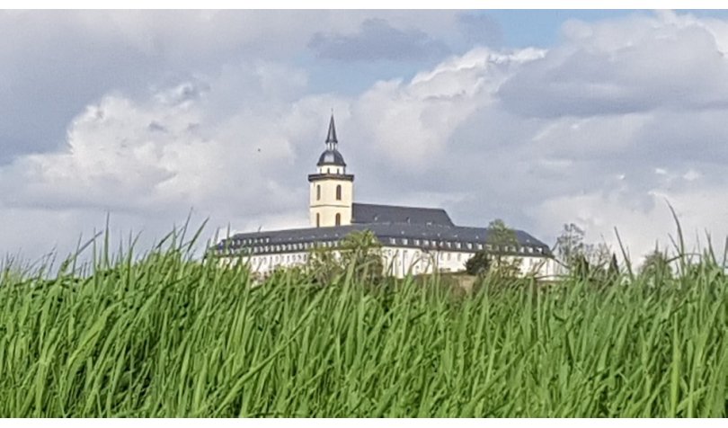 St. Michael und KSI-Gebäude zwischen grünem Gras und bewölktem Himmel