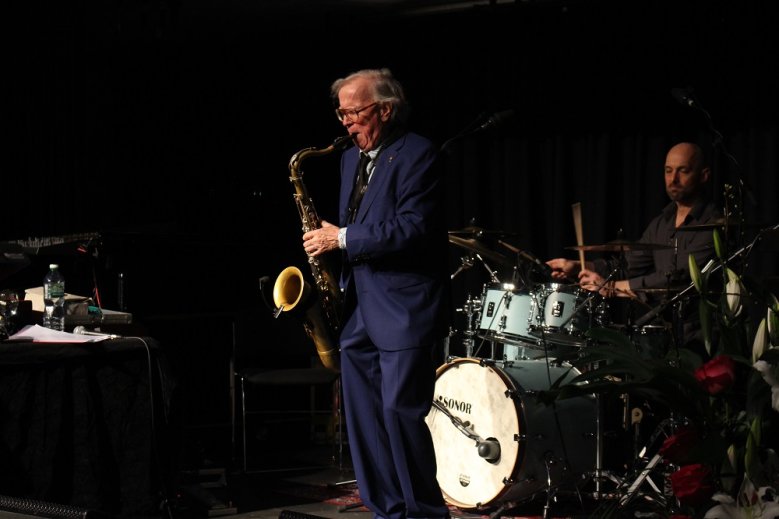2020-05-12_Doldinger Saxophon spielender Klaus Doldinger im blauen Anzug, dahinter ein Schlagzeuger
