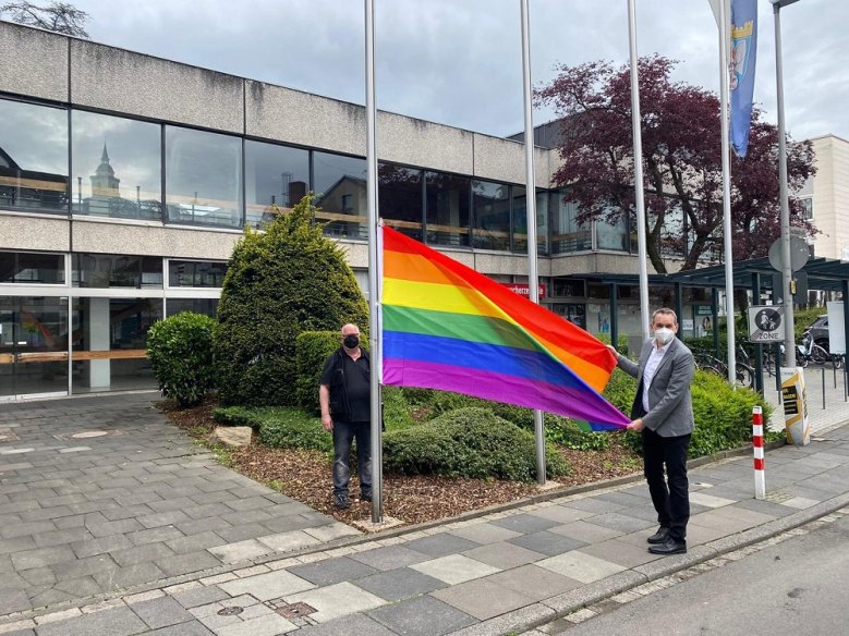 Homophobie Bürgermeister Stefan Rosemann und Hausmeister Anton "Toni" Bäcker hissen die Regenbogenflagge am Rathaus.