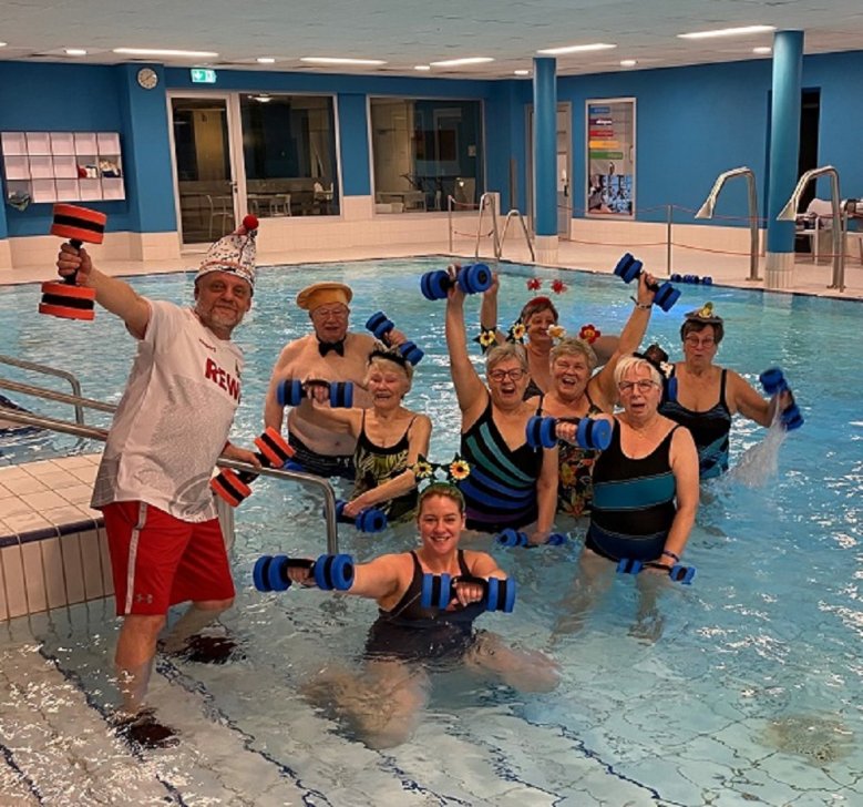 Schwimmschule Lohmann Dirk Lohmann im FC-Trikot mit Senioren-Schwimmschülerinnen und -schülern, verkleidet mit Blumenhüten