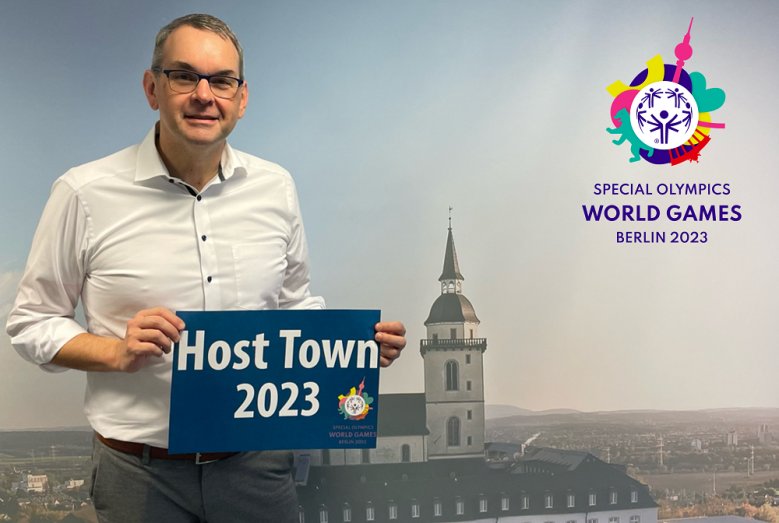 Host Town Bürgermeister Stefan Rosemann mit einem Schild "Host Town 2023"