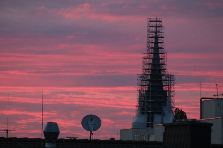 Mittsommerhimmel Abendrot über dem eingerüsteten Turm der Kirche St. Anno.