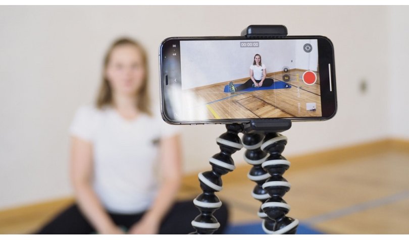 VHS Online-Yoga Smartphone auf einem Stativ, das die Yoga-Einheit einer Dozentin aufzeichnet