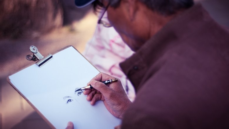 Portraitzeichnen Mann, der ein Augenpaar auf Papier gemalt hat