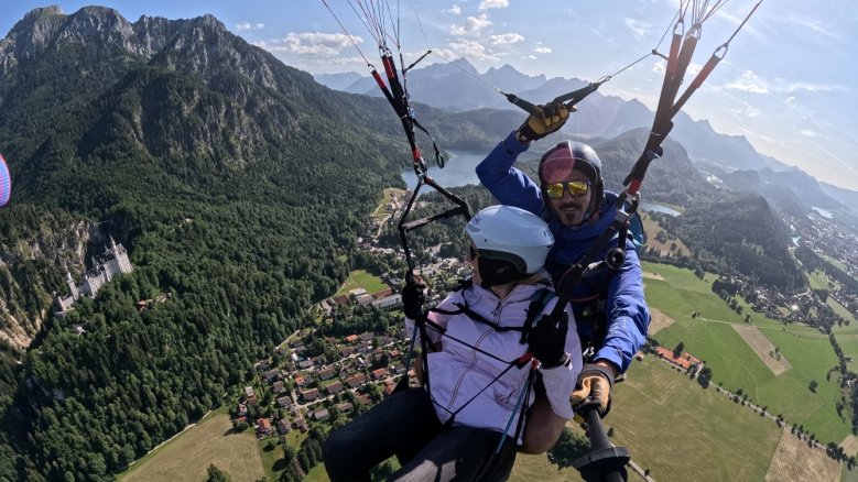 Füssen Paraglider vor Alpenpanorama über dem Schloss Neuschwanstein.