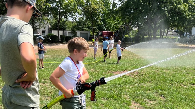 Mini-Siegburg Junge mit Feuerwehrschlauch in den Händen.
