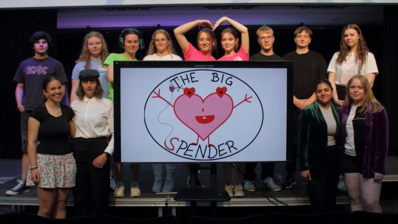 Big Spender Das "Big Spender"-Ensemble des Q1-Theaterkurses vom Anno-Gymnasium, beginnend links neben dem Bildschirm im Uhrzeigersinn: Das Ehepaar Viktor und Martha Braun (Denise Zulauf und Lucy Schade), Kameramann Bruno (Rafael Barreto Bittner), Vicky Laiss (Marie Lukas), Regina Dieks (Morgane Klein), Dr. Charlotte Steinhausen (Talissa Miller), Joceline und Justine Mertens (Johanna Eyckmanns und Livia Ilaender), die Stimmungsmacher und Showassistenten Frank, Eddy und Zoe (Gert-Jan Jansen, Roman Bath und Lena-Marie Wismer) sowie das Moderatorenduo Fiona Norden und Corinna Süden (Karoline Zerwas und Zilan Deger).