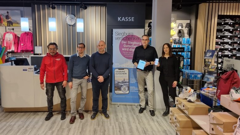 Digitaler Gutschein Guido Dreschmann (Intersport Dreschmann), Ole Erdmann (Amt für Umwelt und Wirtschaft) Sissis Vassiliadis (Verkehrsverein Siegburg), Bürgermeister Stefan Rosemann und Miriam Rousseau (Tourist Information) bei der Präsentation des digitalen Gutscheins.
