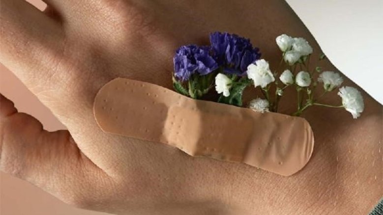 SKM Jahresmagazin Pflaster auf einer Hand, darunter kleben Blumen.