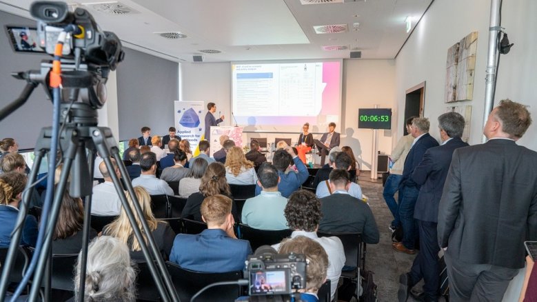 Renewable Materials Conference Bis auf den letzten (Steh-)Platz gefüllter Konferenzraum im Rhein Sieg Forum, Kameras zeichnen den Vortrag auf.