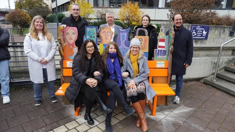 Orange Bank - Gewalt gegen Frauen Die Hennefer Schülerinnen Denzia (h.l.), Manal (v.l.) und Julie (2.v.r.) mit Bürgermeister Stefan Rosemann, Ulrich Feyerabend, Direktor des Amtsgerichts, Marco Herrlich, Geschäftsführer des Evangelischen Jugendwerks, hinten, sowie vorne Eva Zoske und Christiane Pipke, Gleichstellungsbeauftragte der Stadt Siegburg, an der orangen Bank.