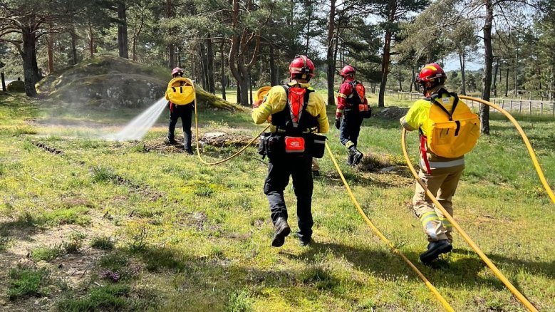 Waldbrandbekämpfung Übung Portugal Vier Feuerwehrleute mit Schläuchen in einem Waldbebiet.