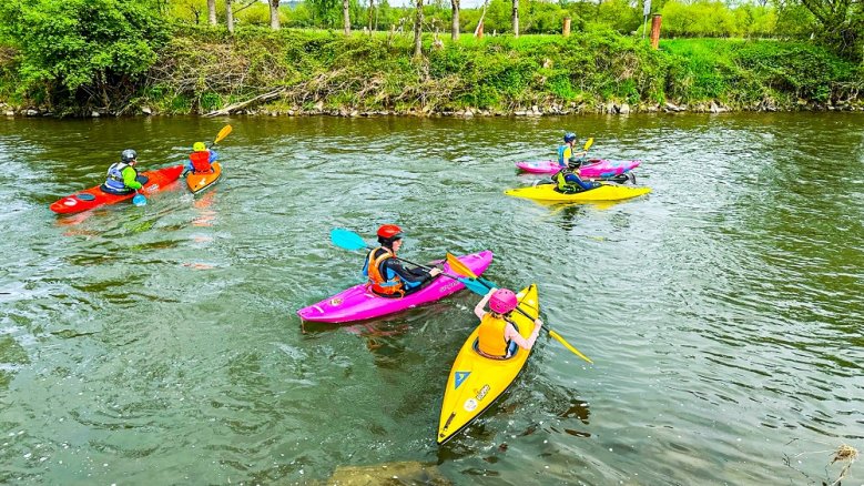 KCD Schnupperpaddeln Kinder im Kajak auf dem Wasser, begleitet von erwachsenen Kanufahrern.