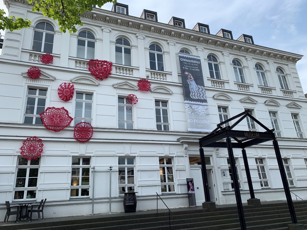 Die Außenfassade des Stadtmuseums mit roten Häkelobjekten von Katharina Krenkel.