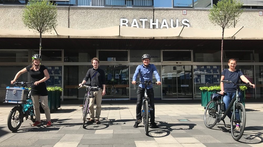 Vier Personen neben ihren Fahrrädern vor dem Siegburger Rathaus.