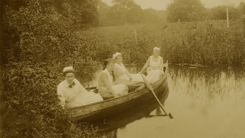 Vier Frauen in einem Holzruderboot.