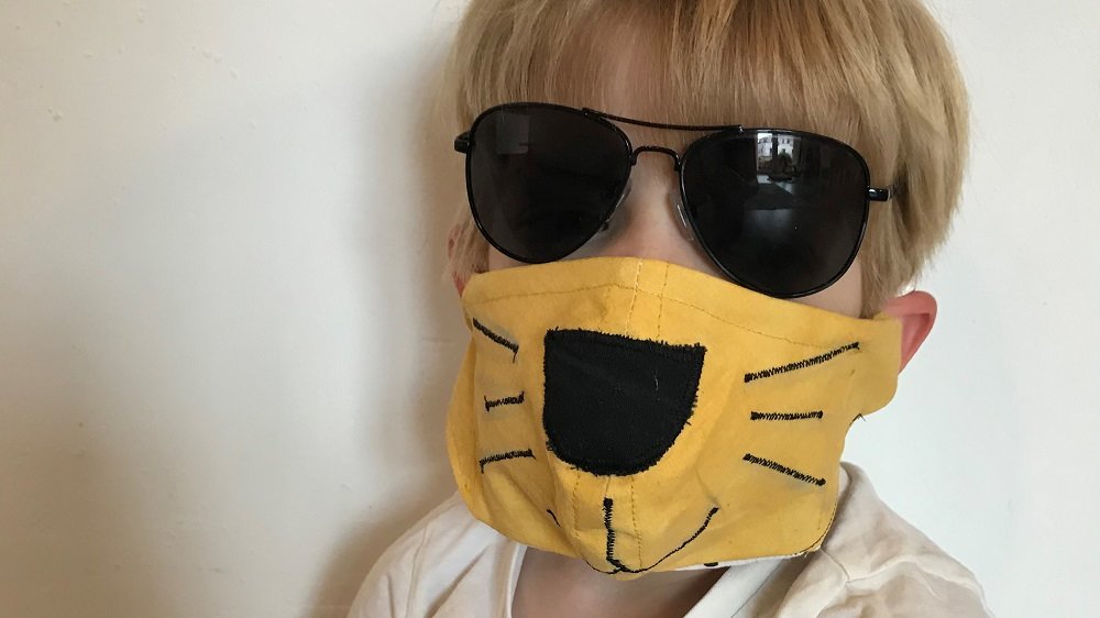 Kind mit Sonnenbrille und Löwen-Maske
