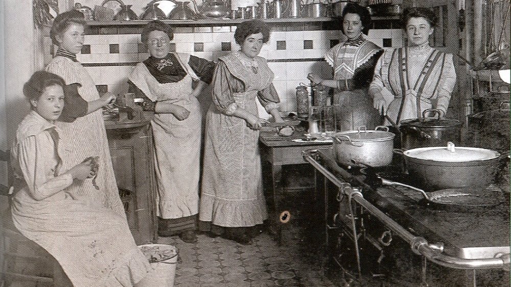 Schwarzweißfoto von Frauen mit Schürzen in einer Küche