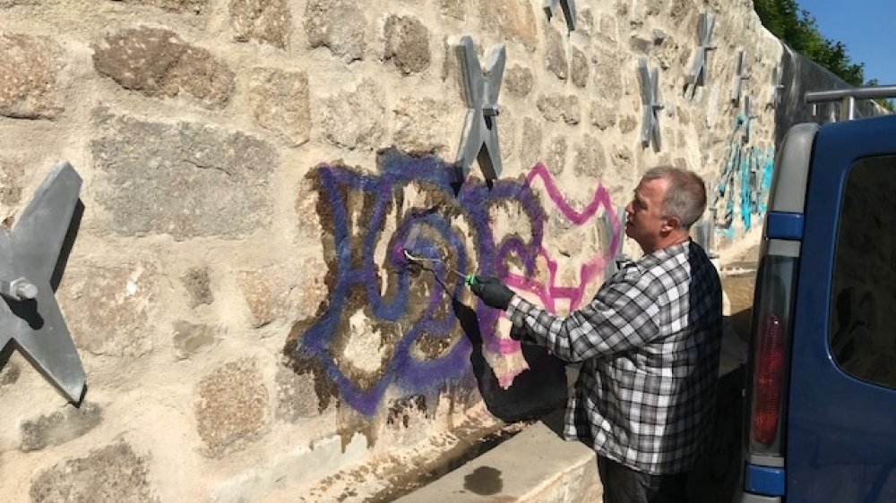 Ein Arbeiter entfernt Graffiti an Mauer