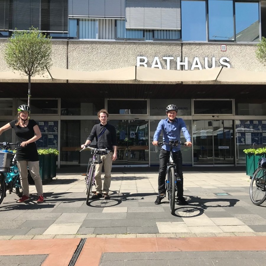 Vier Personen neben ihren Fahrrädern vor dem Siegburger Rathaus.