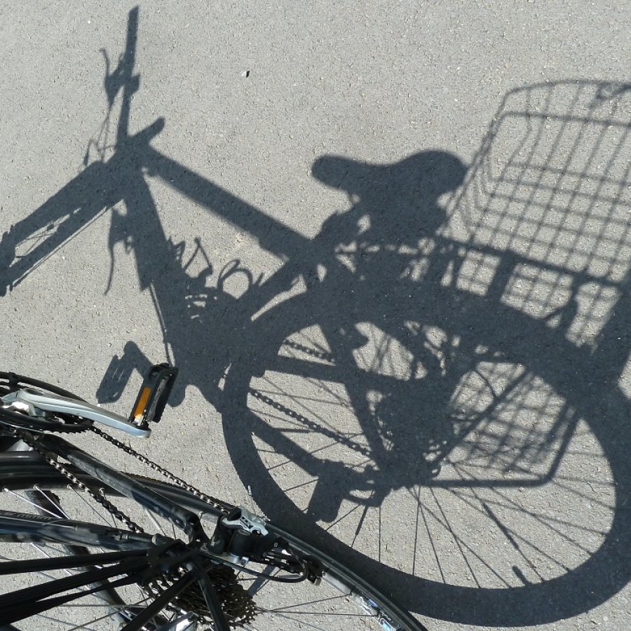 Schatten eines Fahrrads mit Korb auf dem Gepäckträger