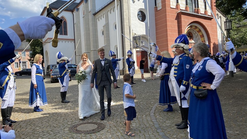 In blau und weiß gekleidete Karnevalisten stehen vor der Kirche St. Servatius Spalier für ein Brautpaar