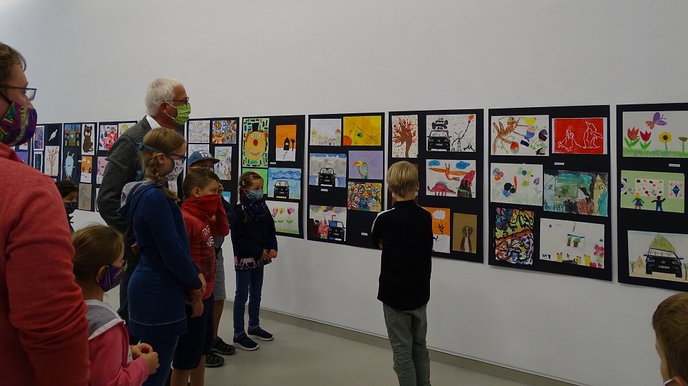 Bürgermeister Franz Huhn betrachtet gemeinsam mit den jungen Künstlern Kinderzeichnungen