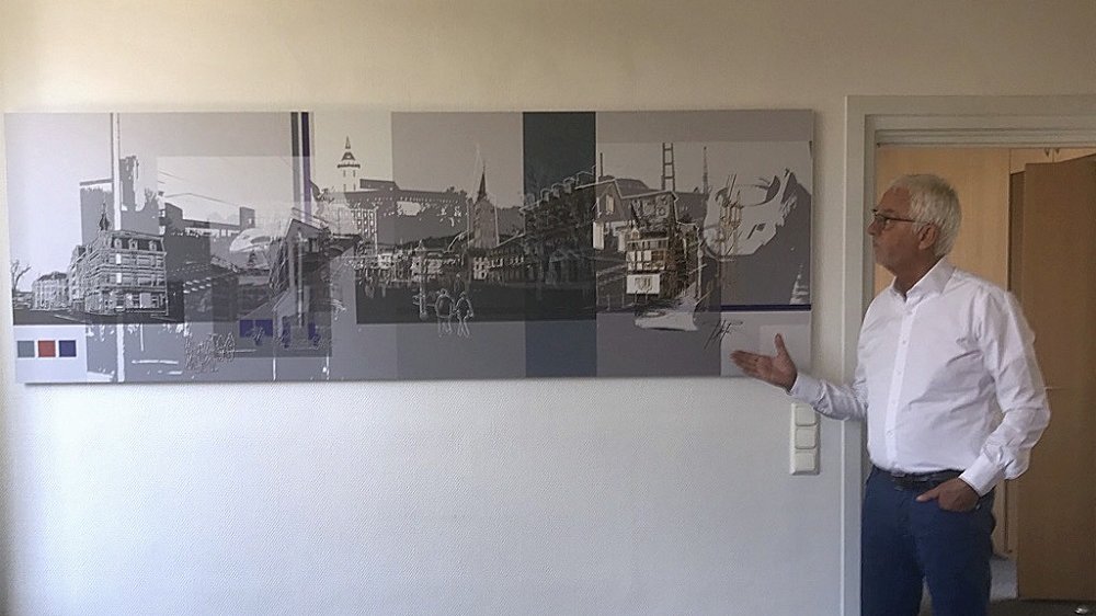 Bürgermeister Franz Huhn neben einer Collage mit Ansichten aus Siegburg