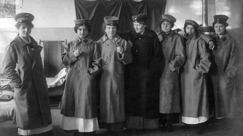 Krankenschwestern 1915 mit Soldatenmänteln, Uniformkappen und Zigaretten in einem Krankensaal des Lazaretts in der Abtei auf dem Michaelsberg