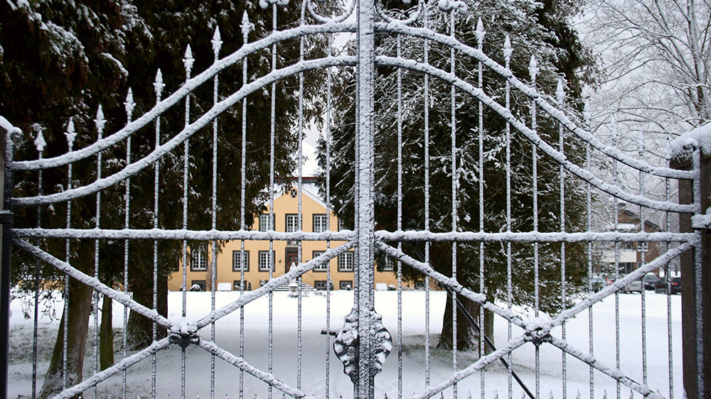 verschneites schmiedeeisernes Tor vor dem alten, historischen Eingangspfad zum Haus zur Mühlen