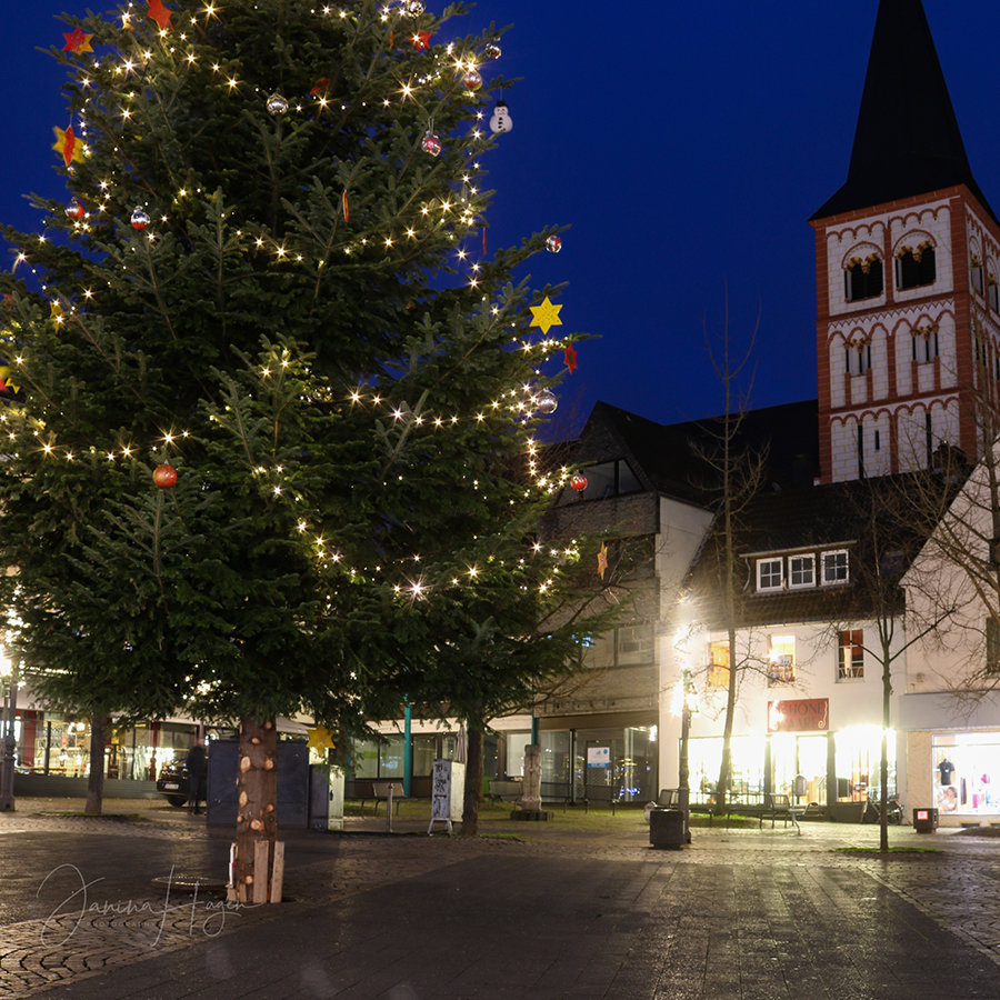 Geschmückter Weihnachtsbaum auf dem leeren Markt am Abend, im Hintergrund die Kirche St. Servatius