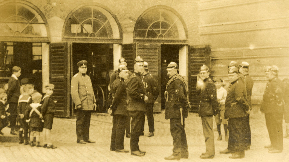 Brandmeister Gerhard Reusch mit Wehrmännern am Feuerwehrhaus zwischen Humperdinckhaus, seinerzeit Amtsgericht und Färberei Schulz, April 1926